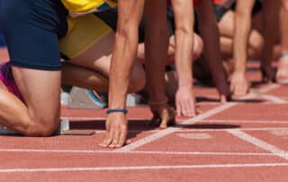 Group of male track athletes on starting blocks.Hands on the sta