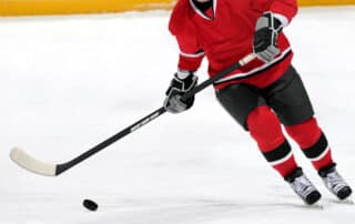 Ice hockey player dribbling puck on rink