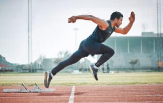 Stadium, man running and athlete on a runner and arena track for sprint race training. Fast, run and sports exercise of a male person in marathon for fitness and workout outdoor on a field for health