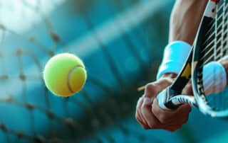 Close-up of muscular arms holding a tennis racket and hitting the ball. Banner championship tennis