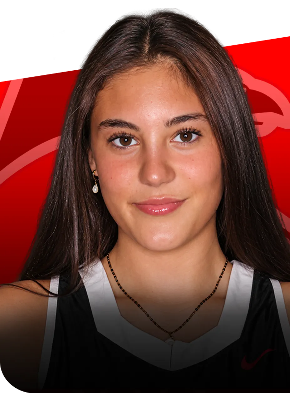 Natalie-Berube-profile-groton-ct Portrait of a young woman with long brown hair wearing a black and white sports jersey against a red background.